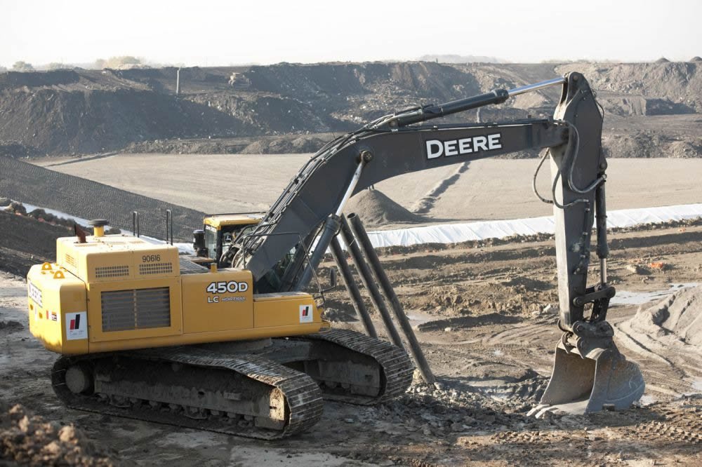 Excavator on the hill with valley in background.